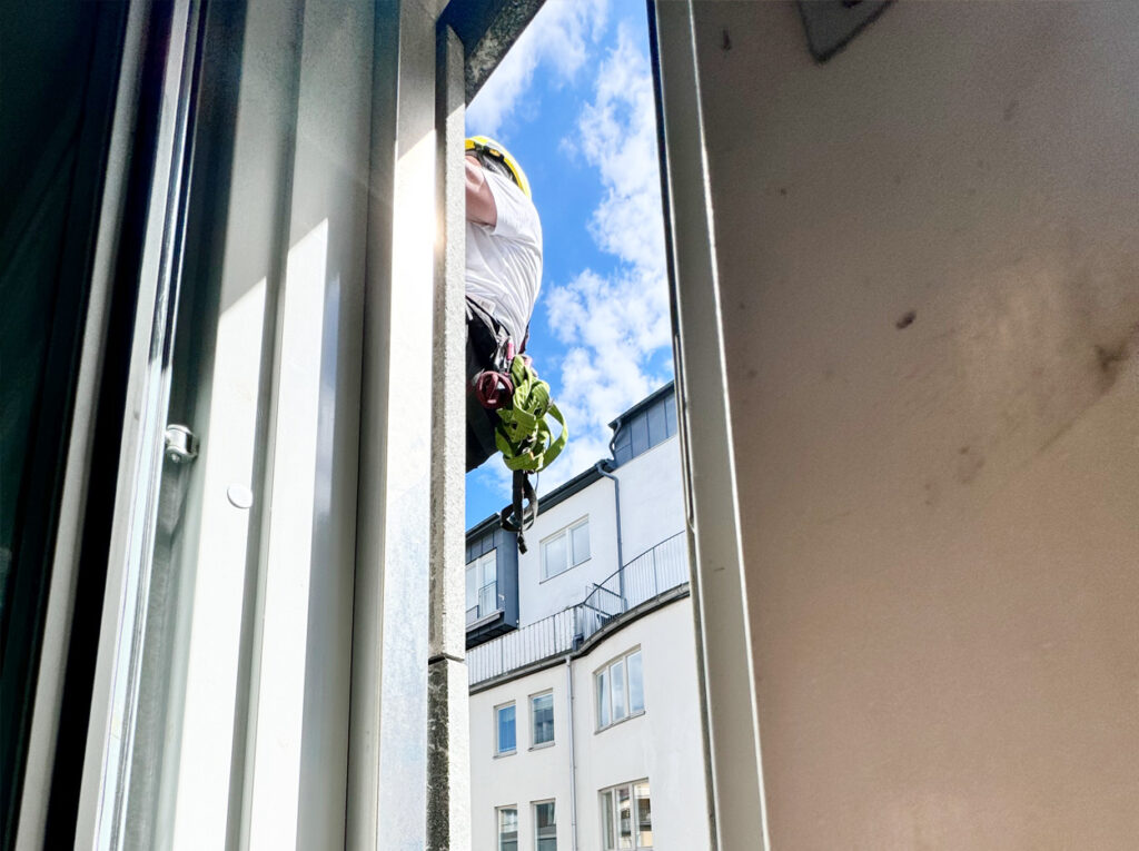 Bild genom ett fönster på en person som genomför höghöjdsarbete